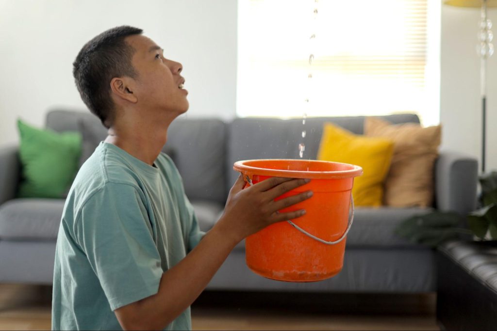 Man catching leaking water in a bucket.