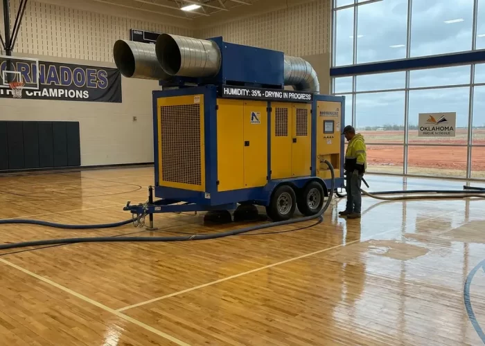 Industrial desiccant dehumidifier drying a hardwood school gymnasium floor in Oklahoma.