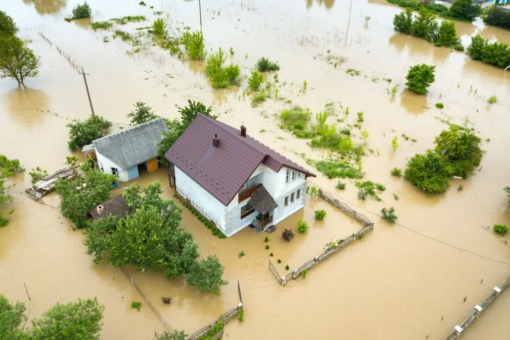 Aerial view of a flooded home with muddy water, highlighting the need for water mitigation services.