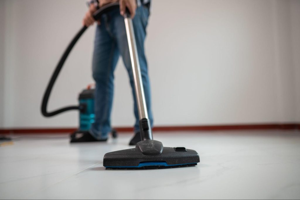 A cropped shot of a man vacuuming a floor.