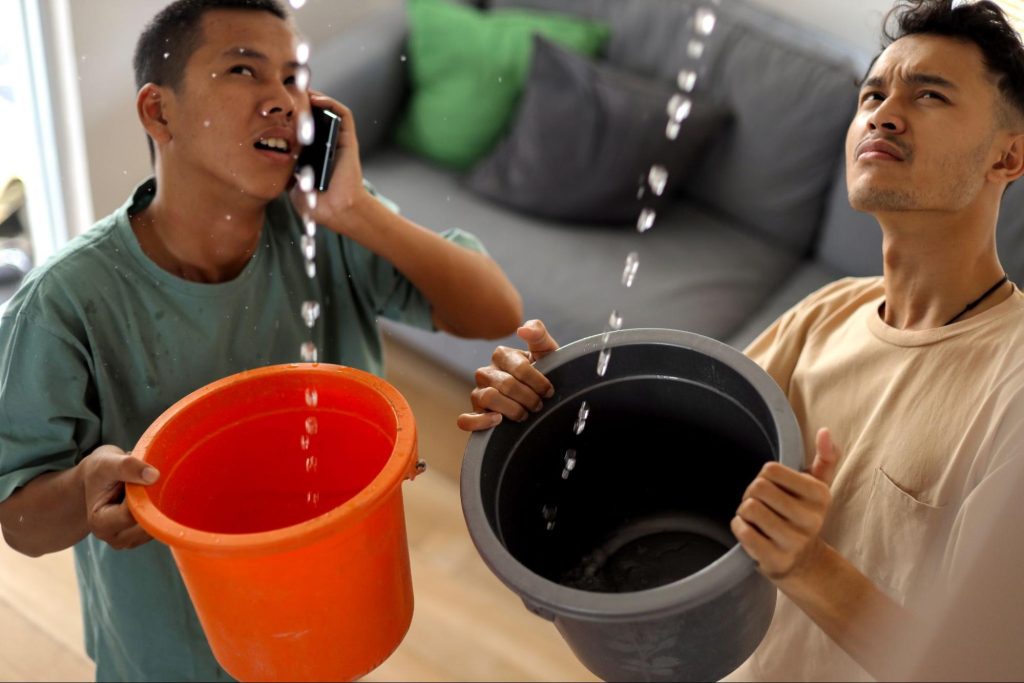 Two men holding buckets with water dripping down. 

